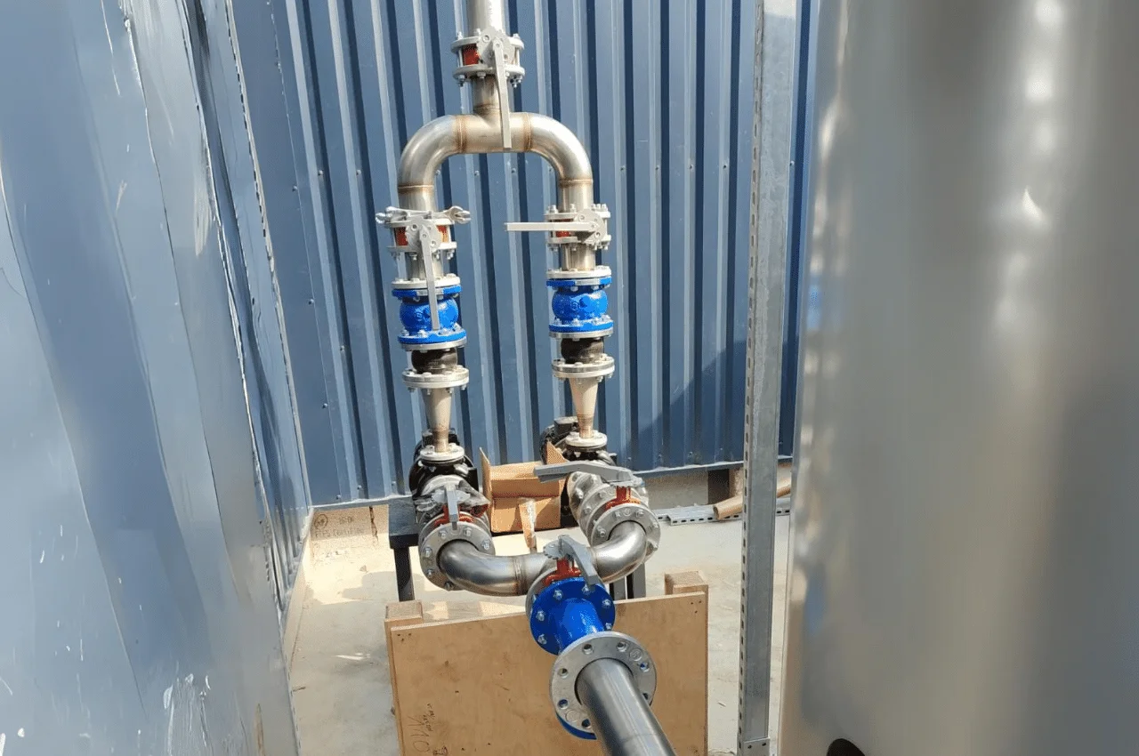 Na zdjęciu widać skomplikowany system rur i zaworów, tworzących złożoną instalację. Konstrukcja ta składa się z wielu różnorodnych elementów połączonych ze sobą w precyzyjny sposób.